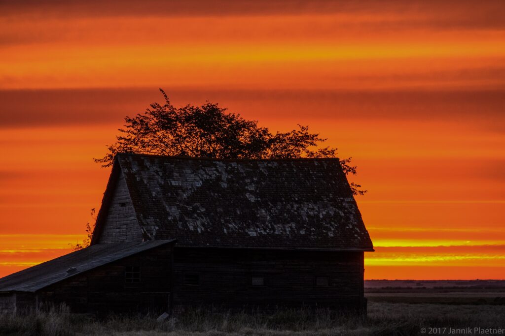 Barn silhouetted against an orange sunset